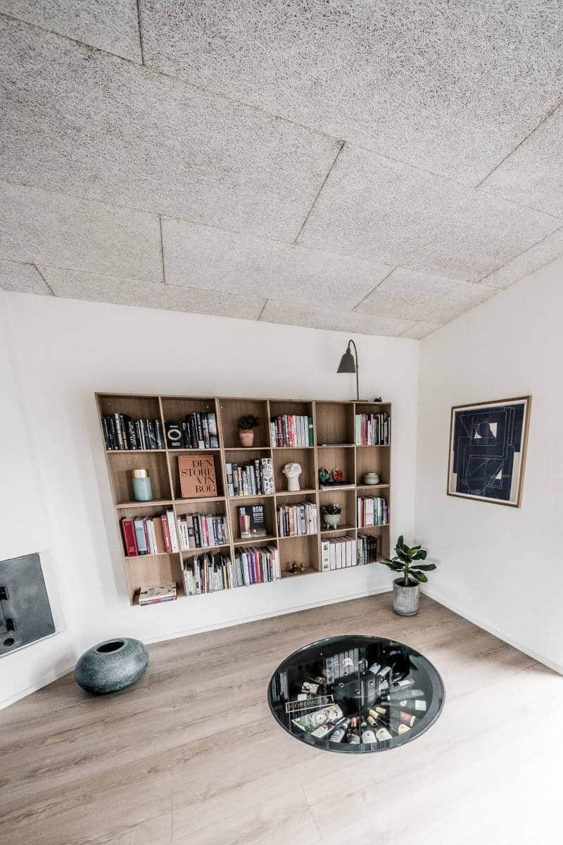 Stue med reol og et rundt glas i gulvet, kælderen lukket.